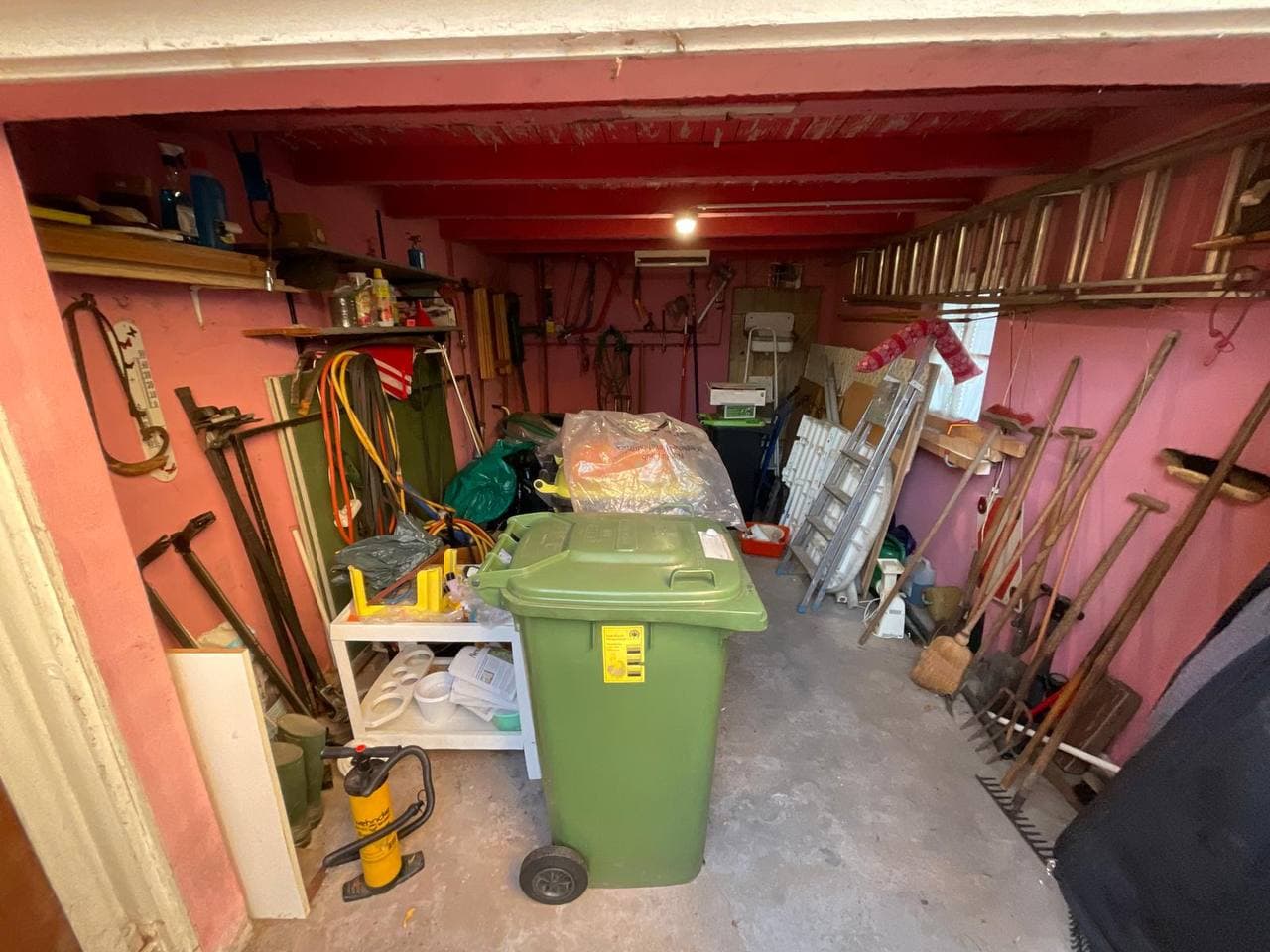 Vollgestellte Garage mit Werkzeug und Mülltonne vor der Räumung